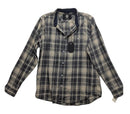 A long-sleeve plaid button-up shirt laid flat on a wrinkled light gray fabric background. The shirt features a beige and dark gray/black plaid pattern with a dark navy collar lining and a black hangtag attached.