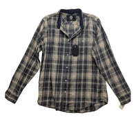 A long-sleeve plaid button-up shirt laid flat on a wrinkled light gray fabric background. The shirt features a beige and dark gray/black plaid pattern with a dark navy collar lining and a black hangtag attached.